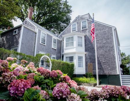 view of historic nantucket home with vibrant flowers and american flag in foreground