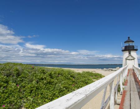 bright blue sky overlooking beach and brant point lighthouse in nantucket