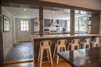 open concept kitchen at 26 pleasant street in downtown nantucket with white counters and backsplash and gray cabinets with modern appliances