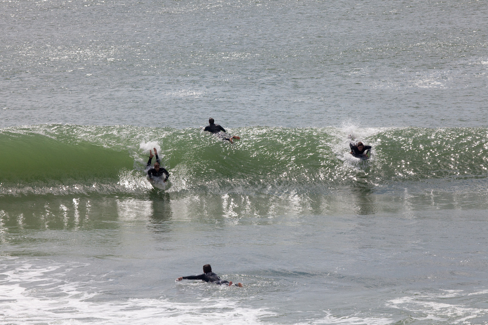 four surfers catching a wave on a nantucket beach 