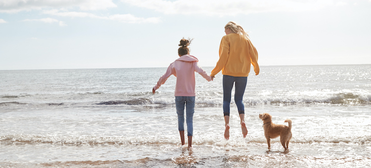 mom daughter and dog on beach